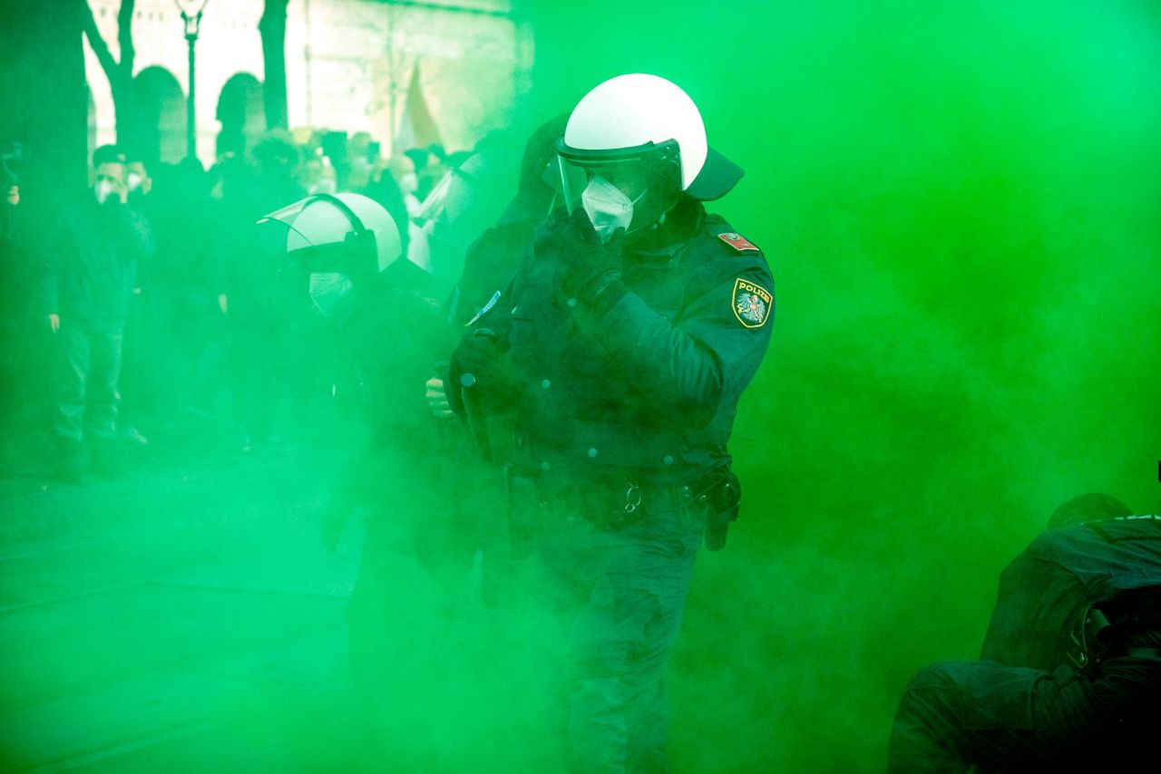 Green smoke envelops a police officer during the protests in Vienna on Saturday.
