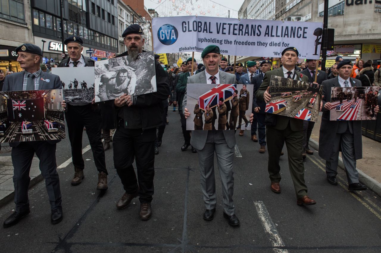 Protesters in London hold photos of veterans' coffins as they protest Covid-19 restrictions on Saturday.