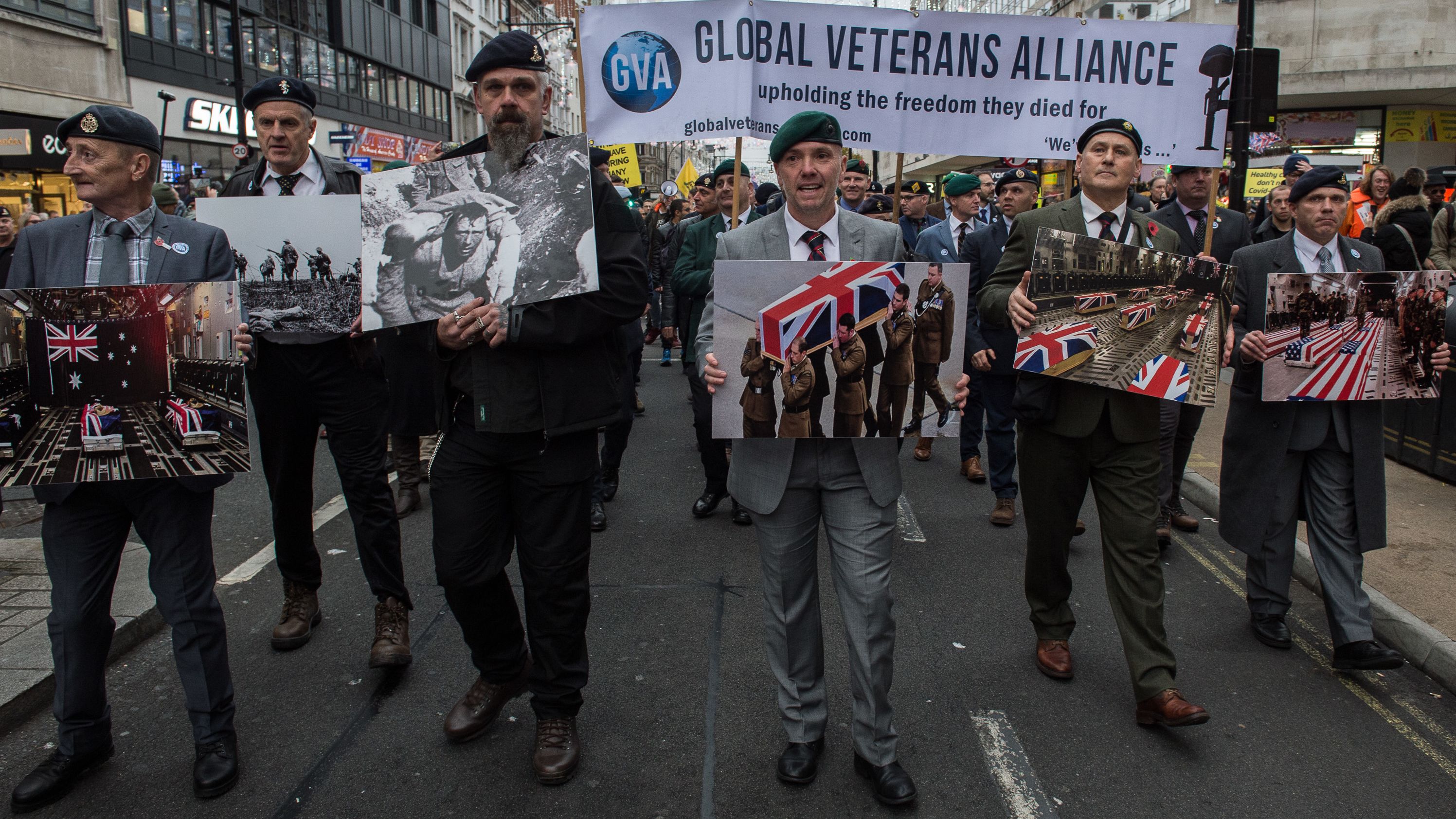 Protesters in London hold photos of veterans' coffins as they protest Covid-19 restrictions on Saturday.