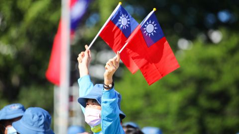 A woman holds Taiwanese flags in front of the Presidential Palace before the National Day celebration starts in Taipei, Taiwan, on October 10, 2021.