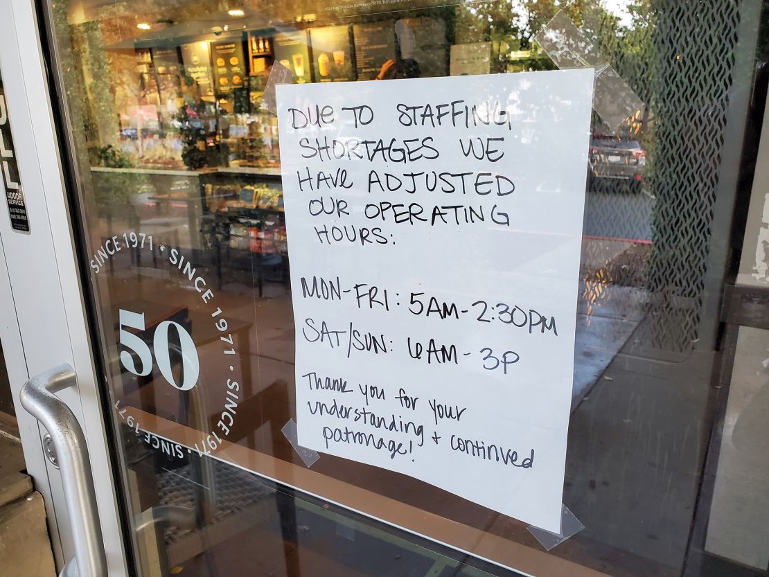A handwritten sign explains reduced hours at a Starbucks Cofee cafe in Lafayette, California, due to staffing shortages, on October 22. 