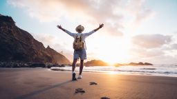 underscord man on beach vacation with arms raised