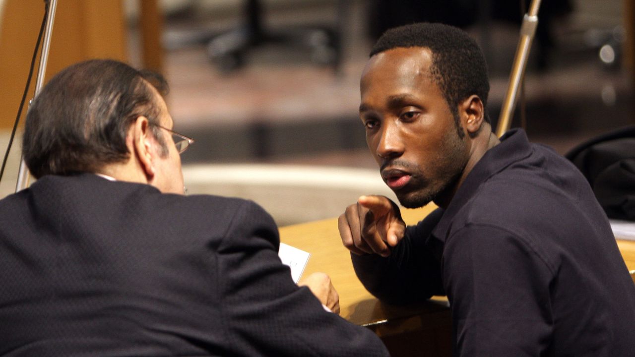Rudy Guede (R) talks to his lawyer's assistant in Perugia courthouse on November 18, 2009.