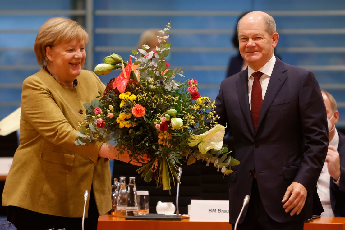Acting Chancellor Angela Merkel receives a bouquet of flowers from acting Finance Minister Olaf Scholz during a cabinet meeting Wednesday.  