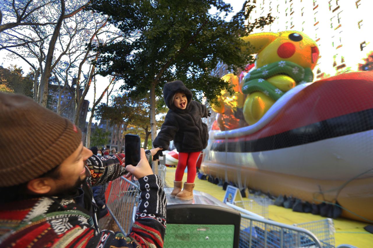Mike Diaz takes a photo of his daughter Luna in front of the Pikachu balloon as the Macy's parade floats are inflated on Wednesday, November 24.