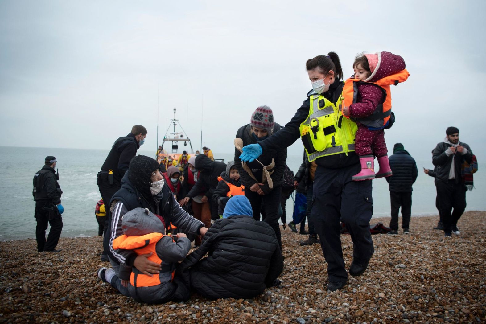 A member of the UK Border Force, right, helps young migrants on a beach in Dungeness, England, on Wednesday, November 24. The migrants had been rescued while crossing the English Channel. British and French leaders have recently <a href="https://www.cnn.com/2021/11/25/europe/uk-france-channel-crossing-deaths-intl-gbr/index.html" target="_blank">ramped up a war of words</a> over dangerous crossings of the English Channel, which have increased dramatically this year.