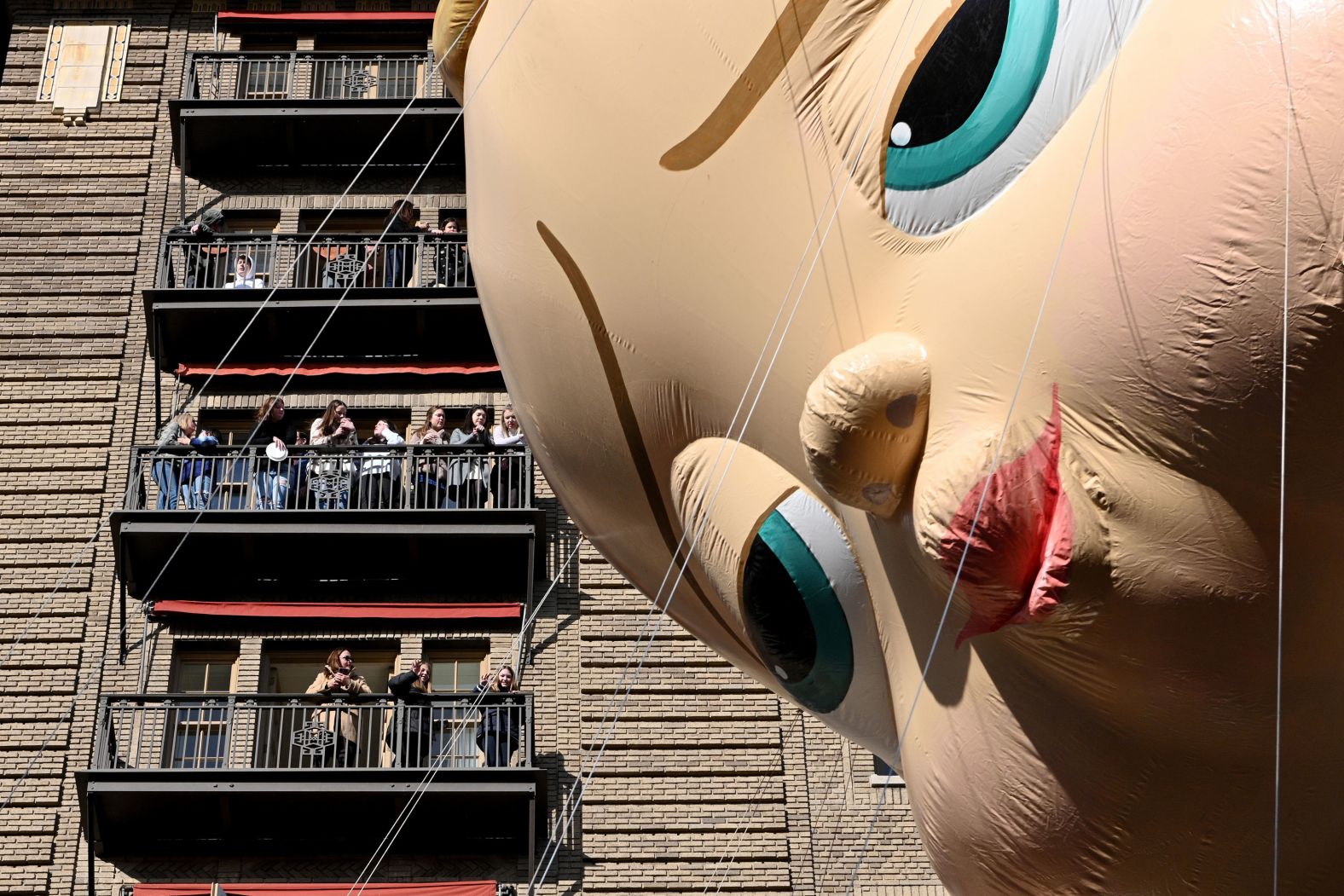The "Boss Baby" balloon passes people standing on their balconies in New York.