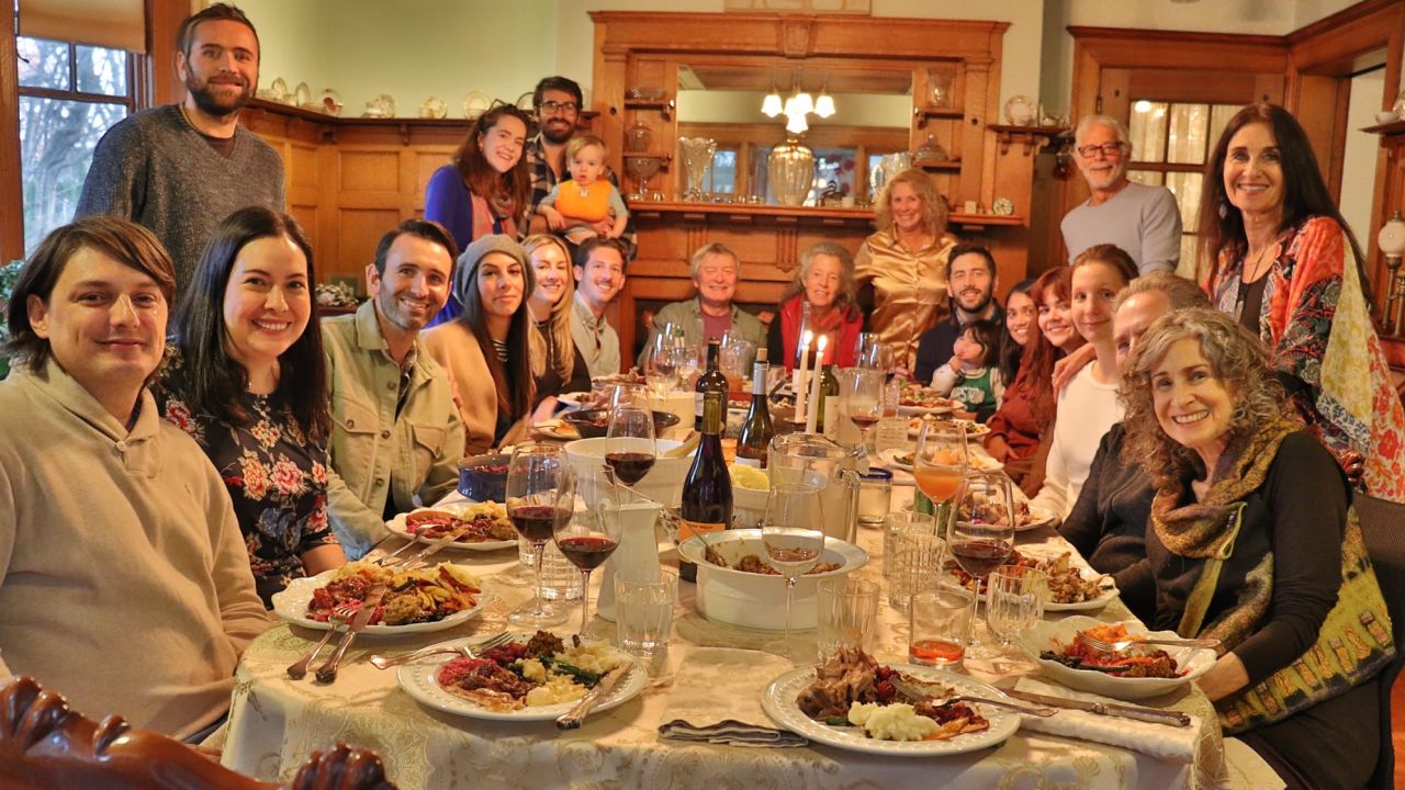 Edward and Susana, seated on the far left, join Carol, standing on the far right, and her family for Thanksgiving dinner.