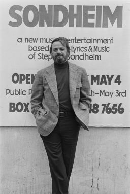 Stephen Sondheim poses in front of a poster for 'Side by Side by Sondheim,' opening on 4 May 1976 at the Mermaid Theatre in London, England, April 1976.