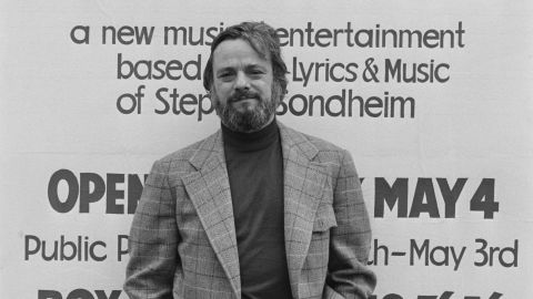 Stephen Sondheim poses in front of a poster for 'Side by Side by Sondheim,' opening on 4 May 1976 at the Mermaid Theatre in London, England, April 1976.