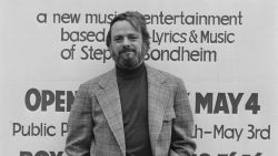 American composer and lyricist Stephen Sondheim poses in front of a poster for 'Side by Side by Sondheim,' opening on 4 May 1976 at the Mermaid Theatre in London, England, April 1976. (Photo by Evening Standard/Hulton Archive/Getty Images)