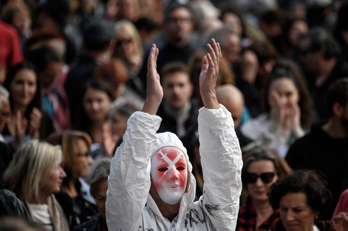 A protester wearing a mask depicting syringes applauds in Geneva, Switzerland, on October 9, 2021, during a rally against coronavirus measures.