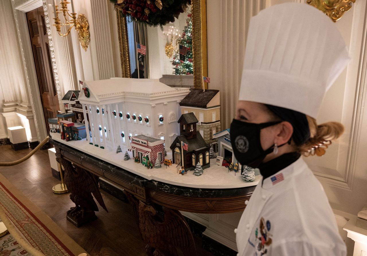 White House pastry chef Susan Morrison is seen near a gingerbread White House in the State Dining Room. The annual gingerbread house -- a 350-pound replica of the original that took Morrison and members of her team several weeks to construct -- was accompanied by other smaller gingerbread and icing "buildings," including a hospital, a fire station, a police station, a warehouse and a school to honor front-line workers.