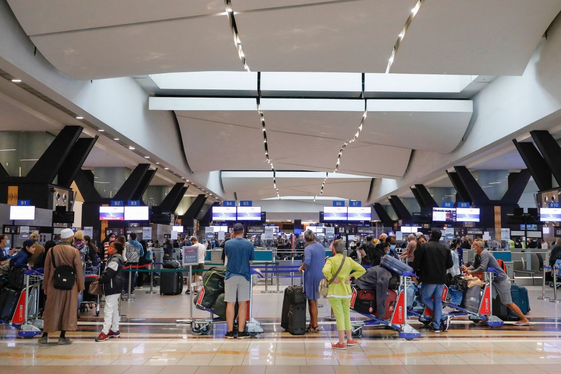 Travelers queue at a check-in counter at OR Tambo International Airport in Johannesburg on November 27, 2021, after several countries banned flights from South Africa.