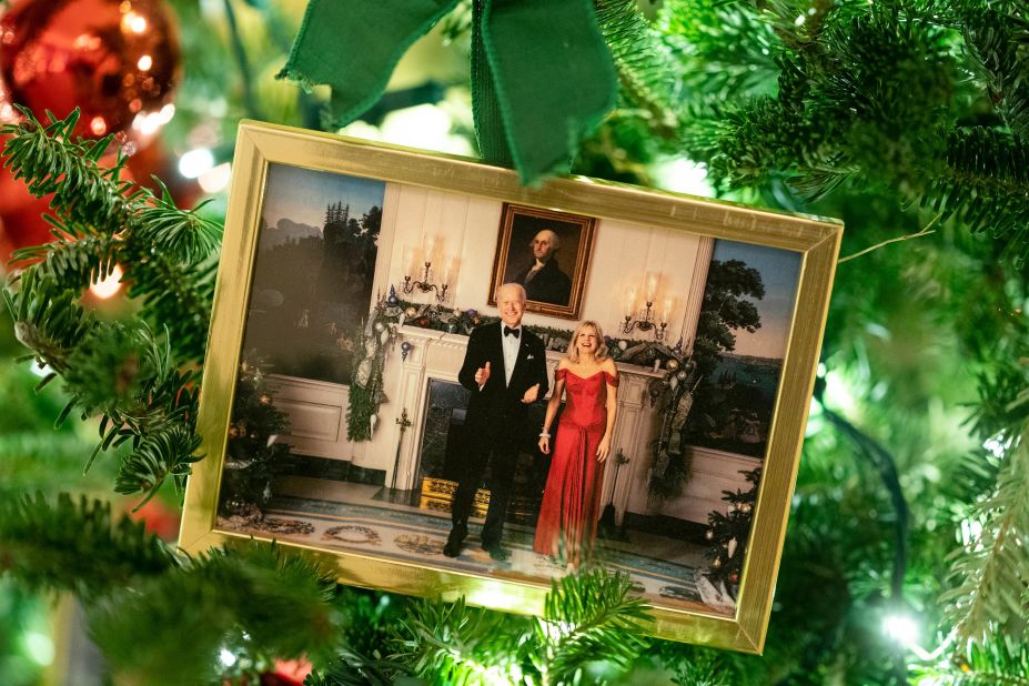 A picture of President Joe Biden and first lady Jill Biden hangs on a tree in the State Dining Room. In the State Dining Room, two large trees are decorated with framed photographs of former first families at the White House during the holidays.