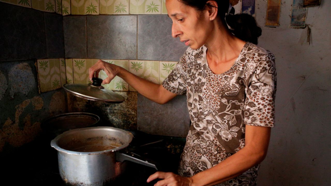 A Venezuelan woman cooks for her family at their home, in a slum in the capital, Caracas, in 2019. 