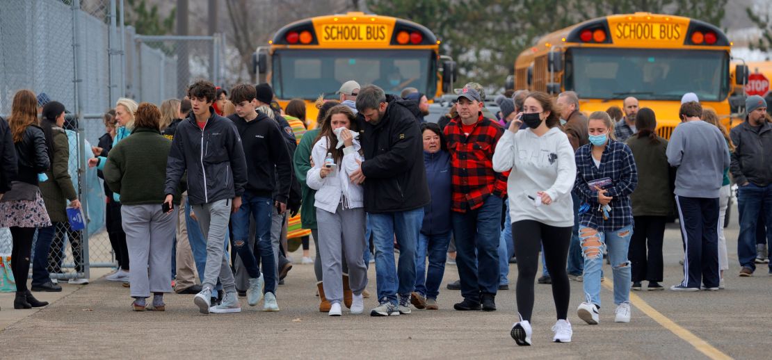 Parents walk with their children away from a grocery store parking lot, where many students gathered after the shooting.
