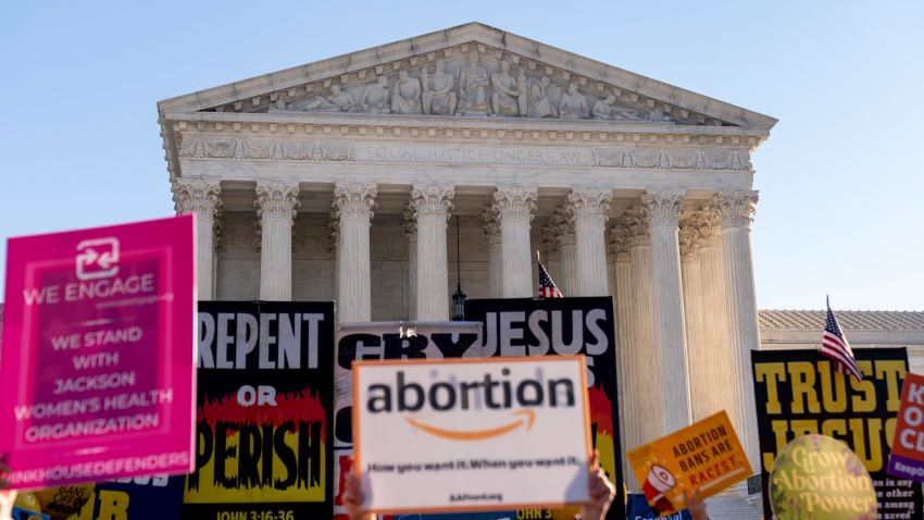 Signs held by abortion rights advocates and anti-abortion protesters are visible as they demonstrate in front of the U.S. Supreme Court, Wednesday, Dec. 1, 2021, in Washington, as the court hears arguments in a case from Mississippi, where a 2018 law would ban abortions after 15 weeks of pregnancy, well before viability.