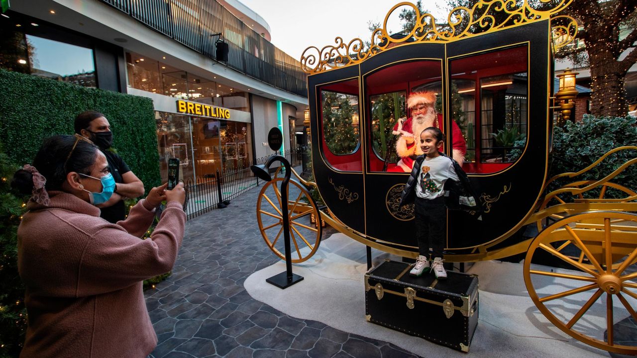 Jeev Anand, 5, is photographed by his mom, Jasmeen, while posing next to Santa Claus in a protective setting in December 2020 at the Westfield Century City shopping mall in Los Angeles.