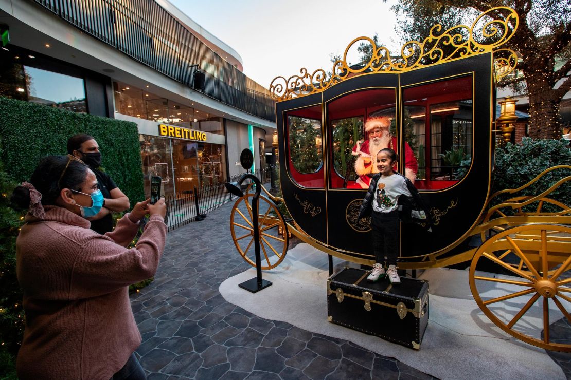 Jeev Anand, 5, is photographed by his mom, Jasmeen, while posing next to Santa Claus in a protective setting in December 2020 at the Westfield Century City shopping mall in Los Angeles. 