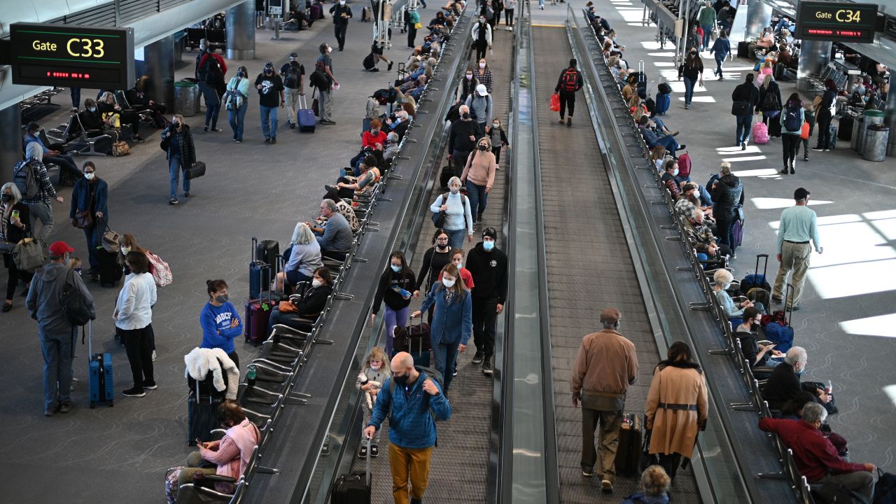 Travelers wear protective face masks at Denver International Airport on November 30, 2021 in Denver, Colorado as concern grows worldwide over the Omicron coronavirus variant. (Photo by Robyn Beck / AFP) (Photo by ROBYN BECK/AFP via Getty Images)