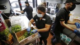 Juan Jimenez, left, at the drive-through window, general manger Maggie Briceno preparing peppers and Daniel Rodriguez, right, delivering food in the busy kitchen of the El Pollo Loco restaurant in Agoura Hills on August 18, 2021.  