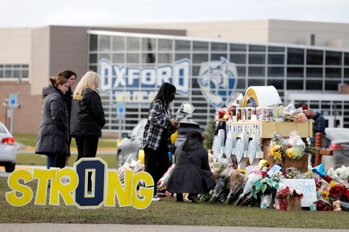 People gather at the memorial for the dead and wounded outside of Oxford High School in Oxford, Michigan on December 3, 2021. - The parents of a 15-year-old boy who shot dead four students at a high school in the US state of Michigan with a gun bought for him by his father just days earlier were charged with involuntary manslaughter.