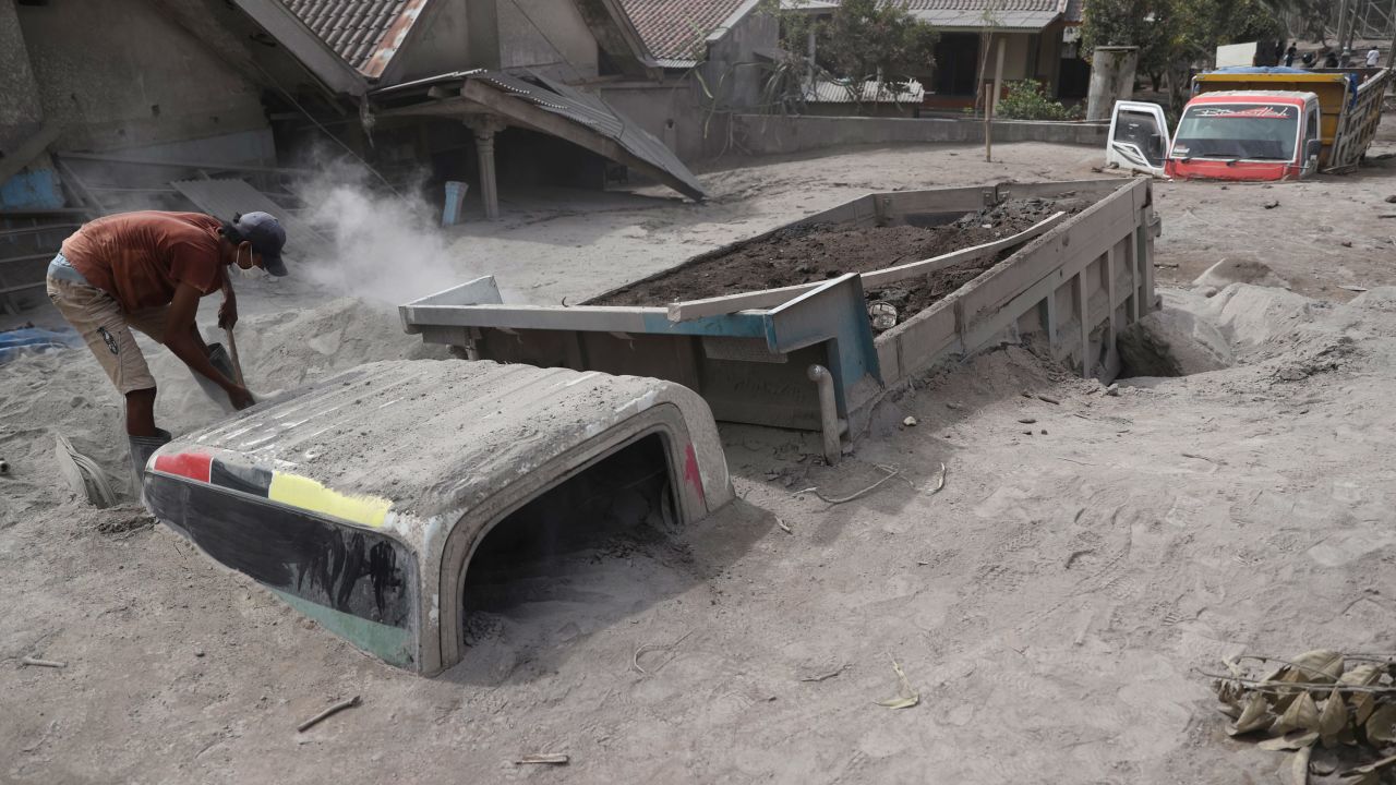 A man inspects a truck buried in the ash following the eruption of Mount Semeru in Lumajang district.