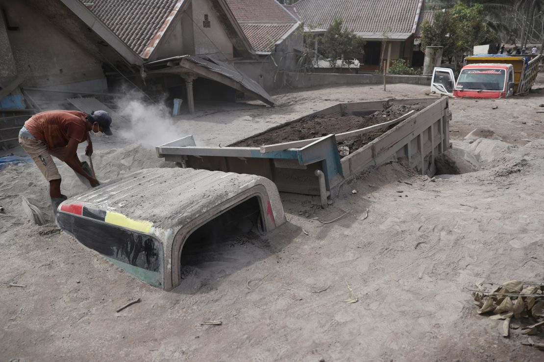 A man inspects a truck buried in the ash following the eruption of Mount Semeru in Lumajang district.
