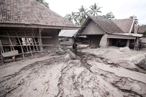 A man stands amid houses that were covered by volcanic ash in the village of Sumberwuluh.