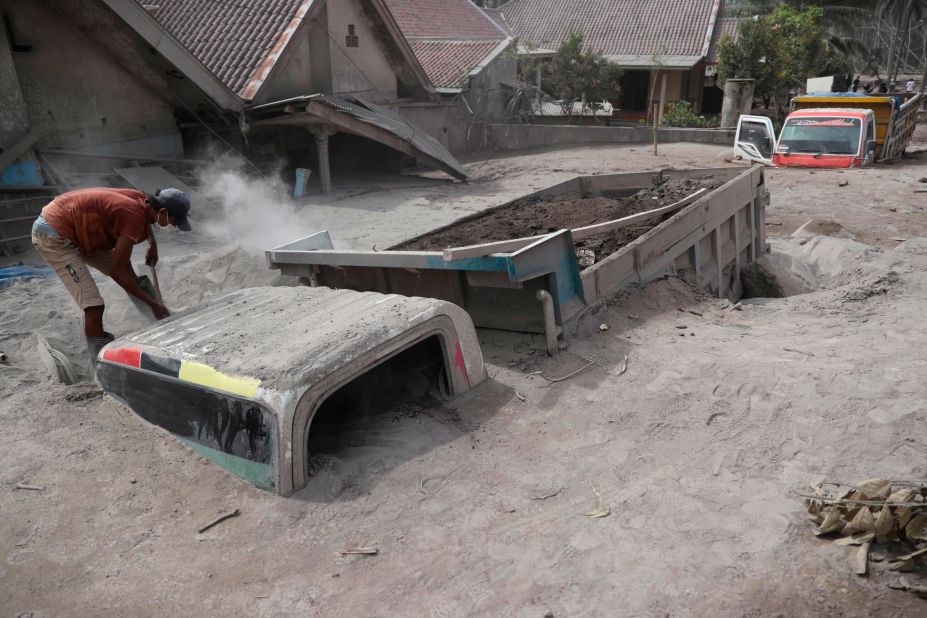 A man inspects a truck buried in the ash on Sunday.