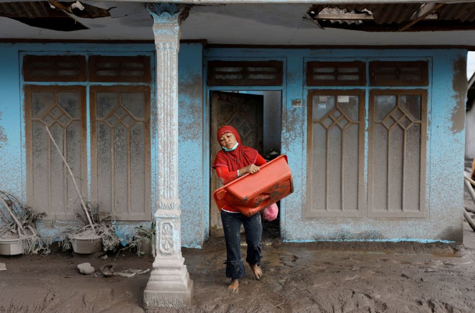 Siti Animah, 42, gathers usable goods from her damaged house Curah Kobokan village, Pronojiwo district, on Tuesday.