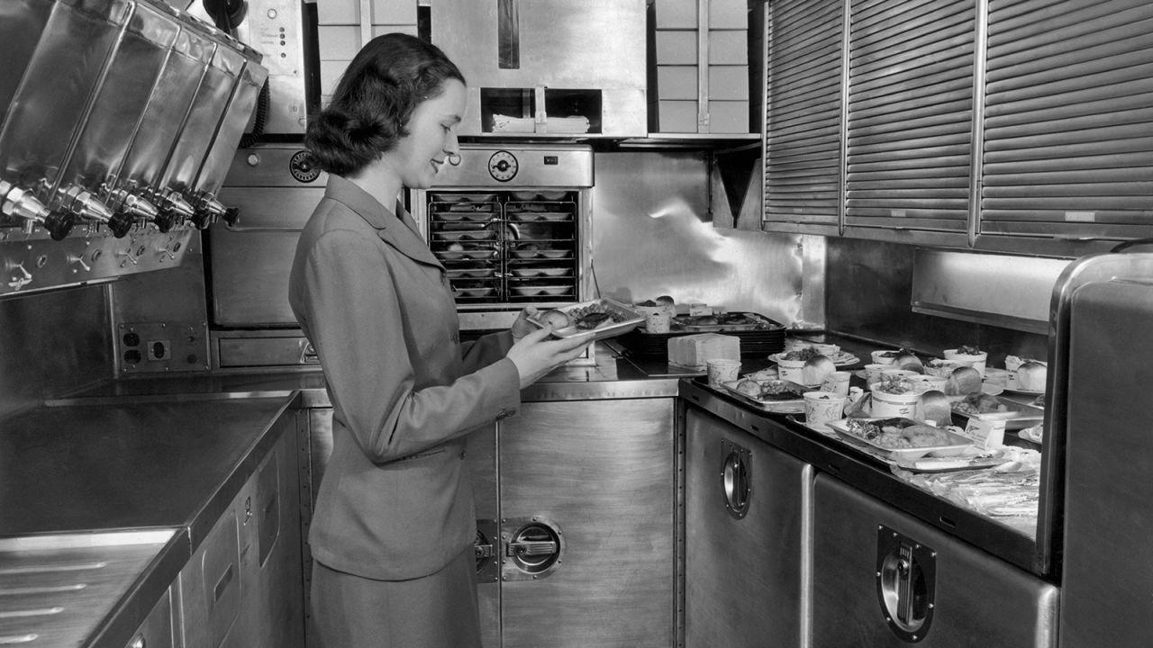 A Pan American World Airways flight attendant preparing in-flight meals in the galley of an airliner, circa 1950.