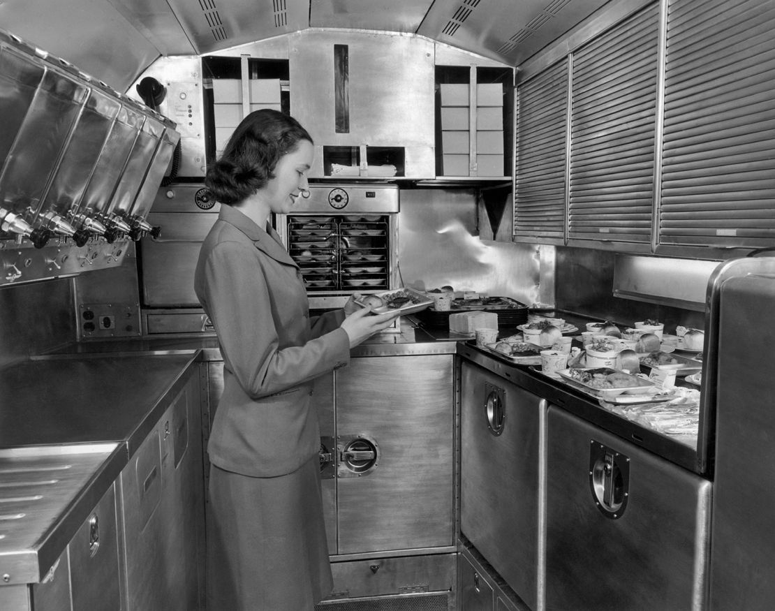 A Pan American World Airways flight attendant preparing in-flight meals in the galley of an airliner, circa 1950.