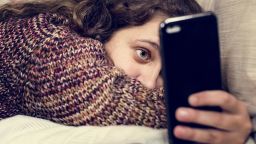 Teenage girl using a smartphone on a bed social media and addiction concept