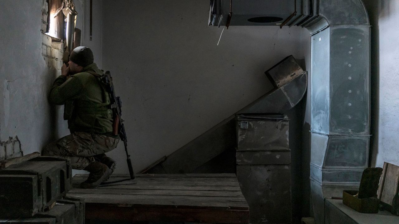 Kolya, a Ukrainian soldier, uses a hand-held periscope to view the positions of Russian-backed forces from a building on the front line on December 8, 2021 in Marinka, Ukraine. 