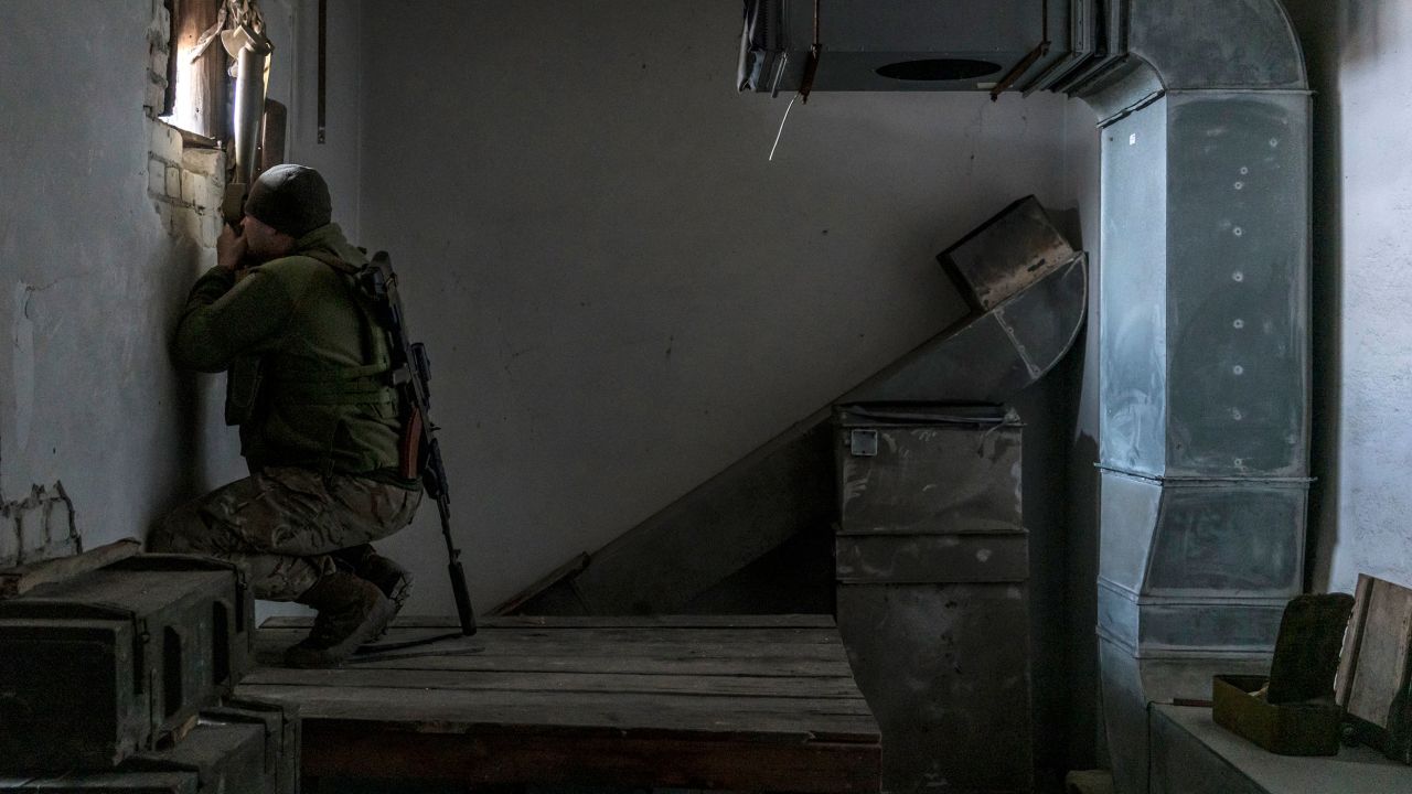 Kolya, a Ukrainian soldier, uses a hand-held periscope to view the positions of Russian-backed forces from a building on the front line on December 8, 2021 in Marinka, Ukraine.