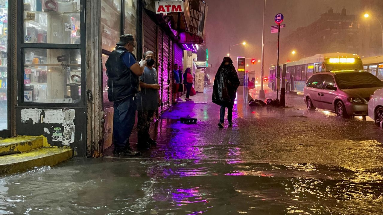 New Yorkers wade through flooded streets brought by extreme rainfall from the remnants of Hurricane Ida on September 2021, in the Bronx borough of New York City.