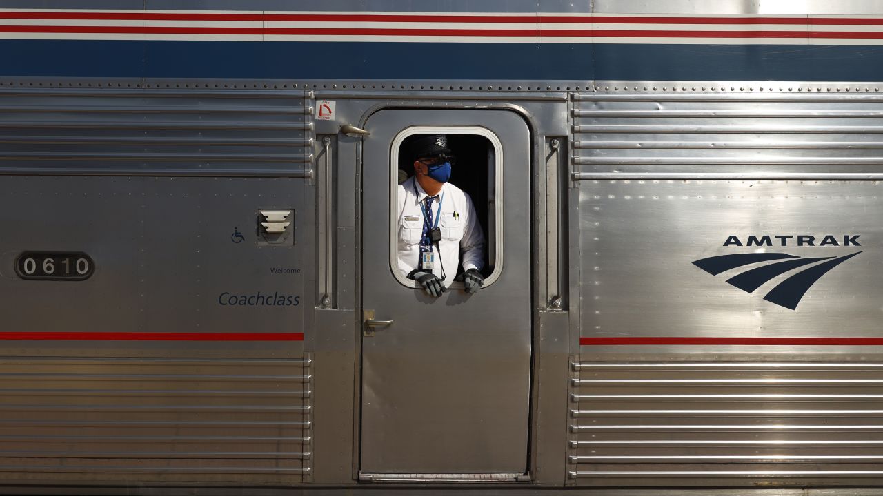 An Amtrak conductor wearing a protective mask looks down the train platform at the Galesburg, Illinois, station.