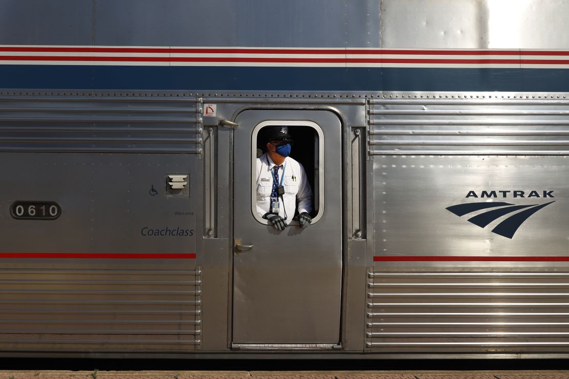 An Amtrak conductor wearing a protective mask looks down the train platform at the Galesburg, Illinois, station. 