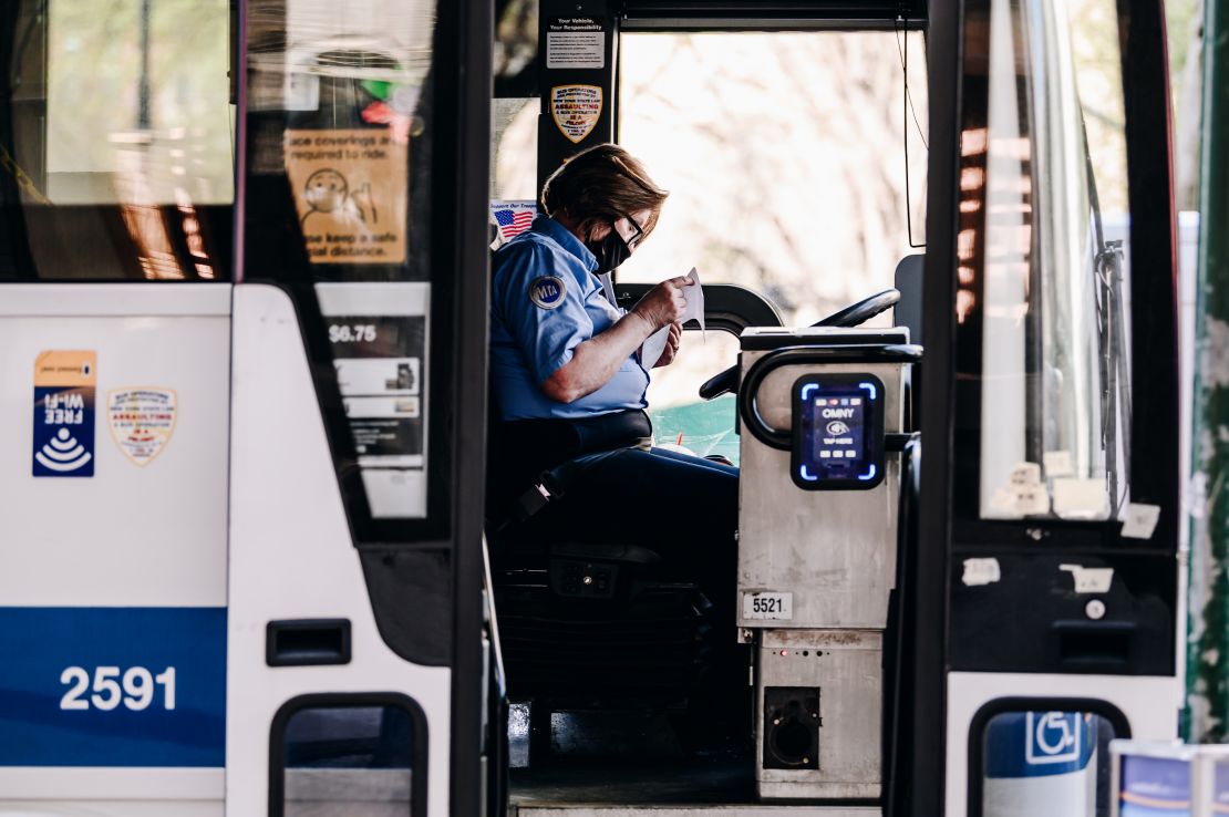 A bus driver wears a protective mask while picking up passengers at a bus stop in New York.