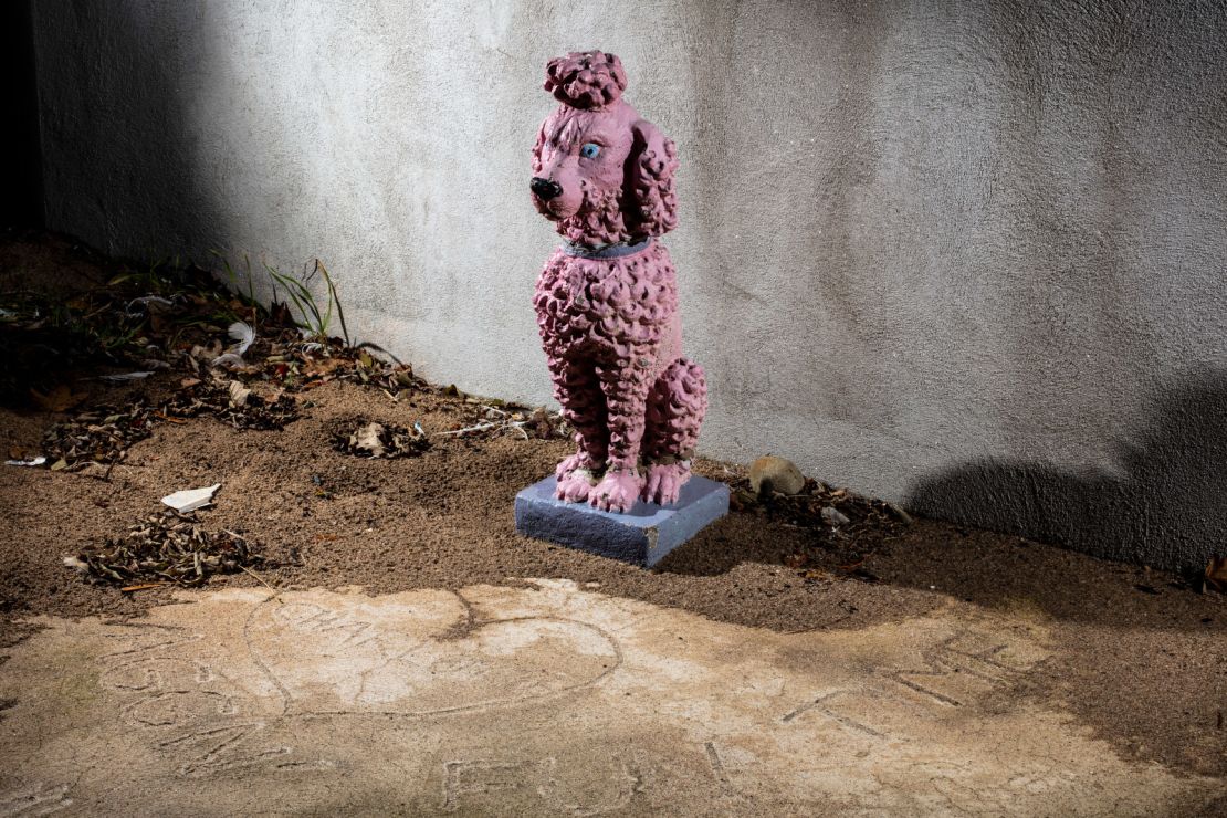 A statue of a dog sits next to a memorial plaque at a playground dedicated to Charlotte Bacon in West Haven, Connecticut.