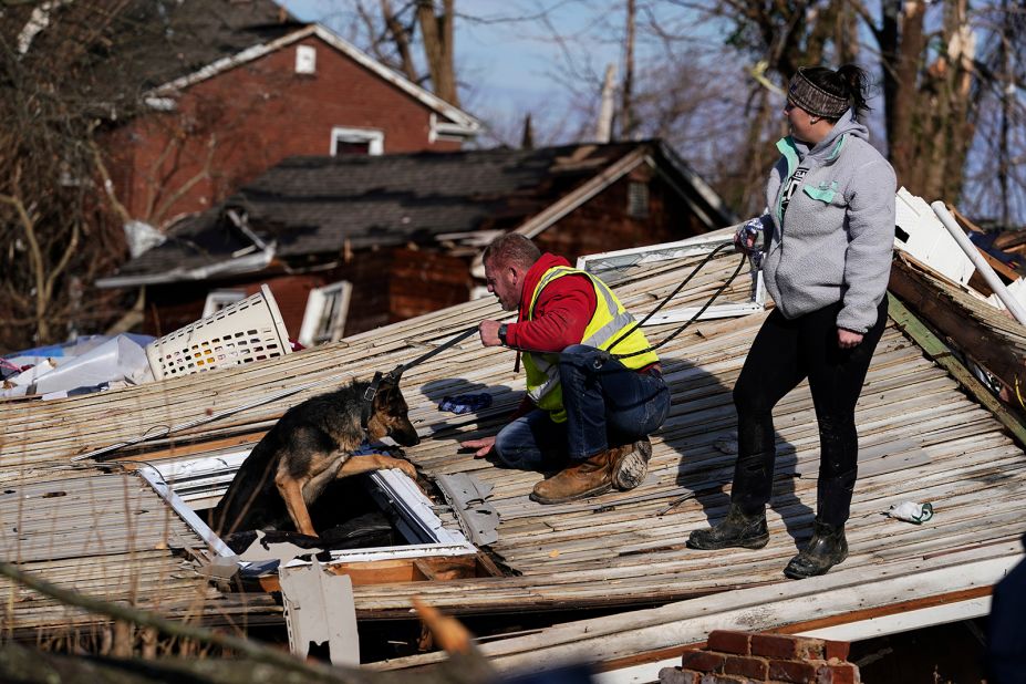 Chris Buchanan, center, and Niki Thompson, right, attempt to rescue Cheyenne, a dog, from a tornado-damaged home in Mayfield on Saturday.
