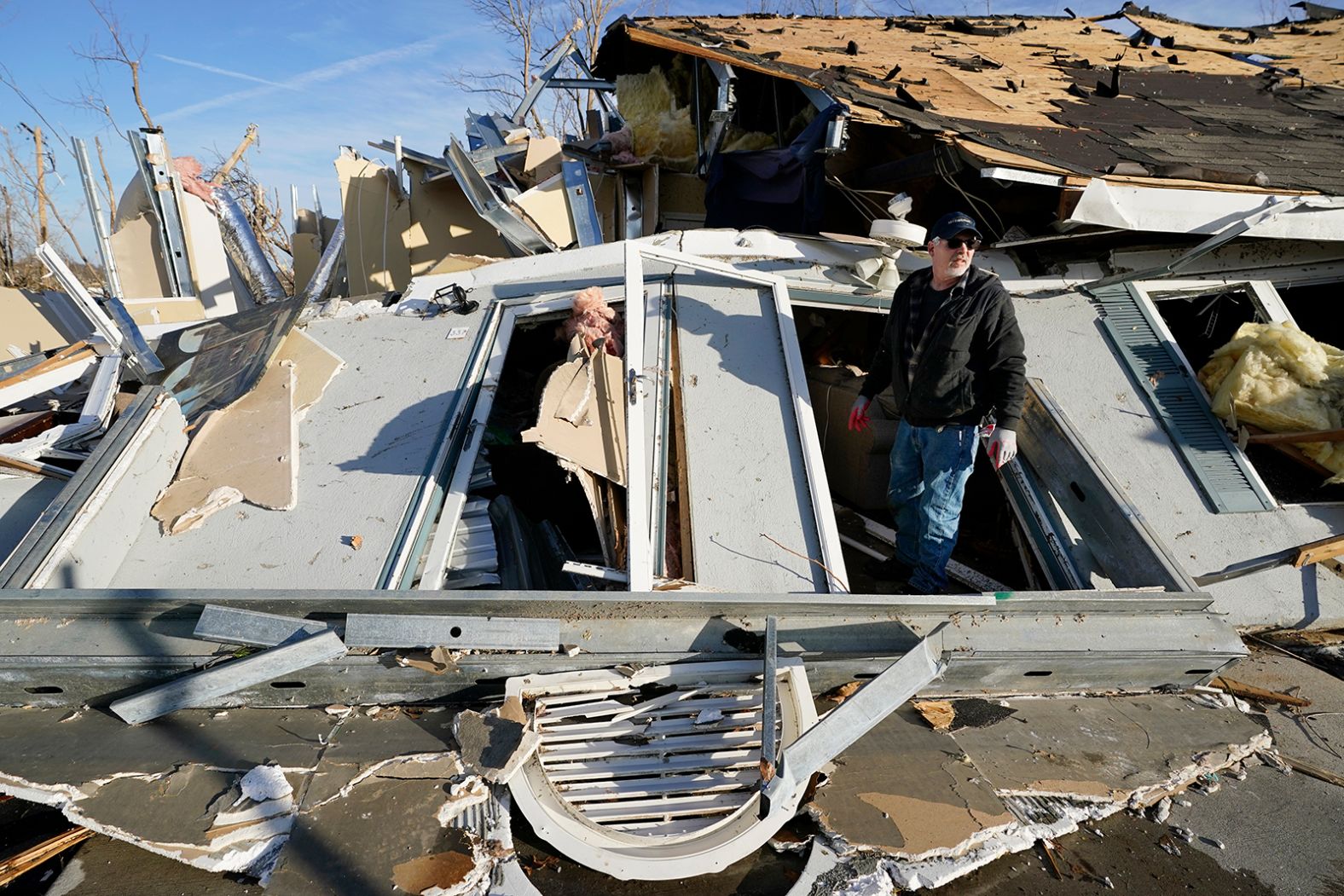 Kenny Sanford exits his mother-in-law's apartment through a collapsed wall on Saturday in Mayfield.