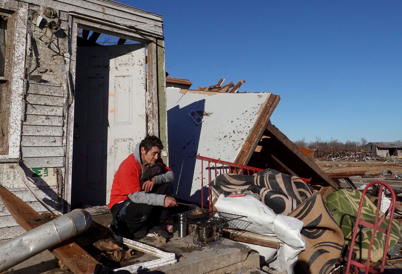 James Strickland prepares breakfast on the porch of his father's home on December 12 in Mayfield.