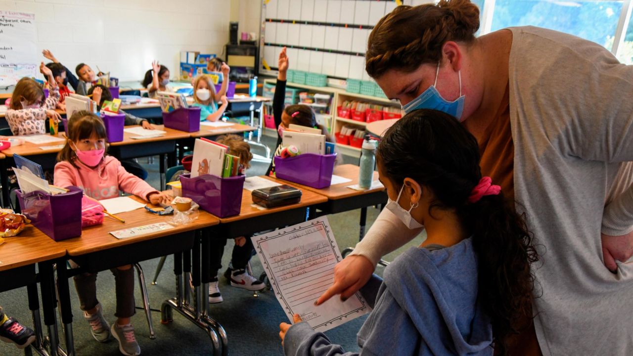 A second grade teacher at Colin L. Powell Elementary School helps a student read aloud a letter they wrote to the family of Colin Powell after his death due to Covid-19 complications.