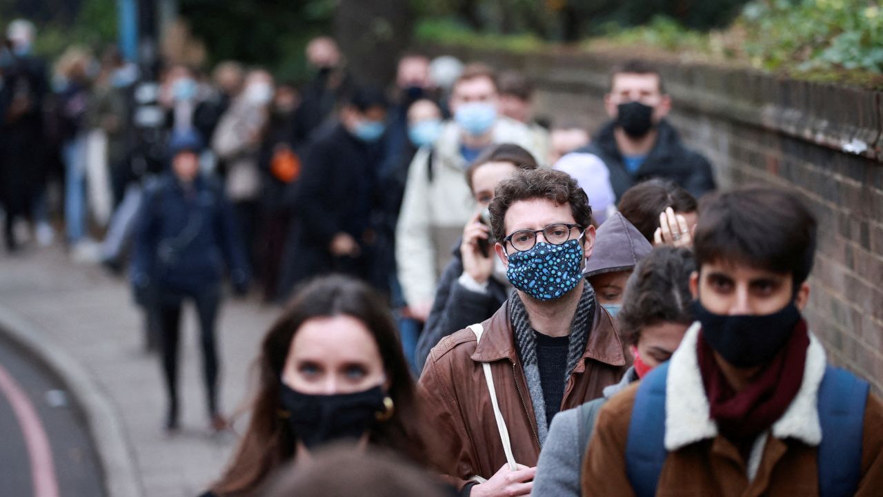 People queue for their booster dose outside a vaccination center in London.