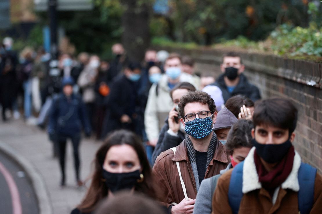 People queue for their booster dose outside a vaccination center in London.