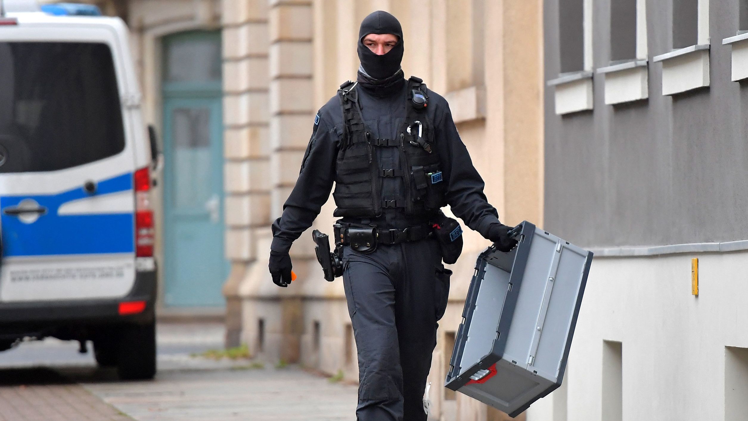 A police officer carries a box during raids in several locations in Dresden, Germany, on Wednesday.
