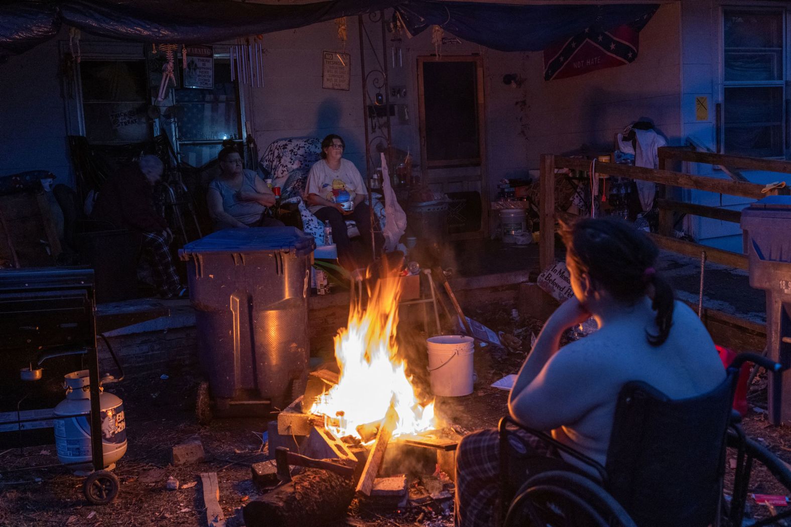 Members of the Bowlin family keep warm next to a wood fire in the front yard of their home on December 14, after losing power in the aftermath of a tornado in Mayfield, Kentucky.